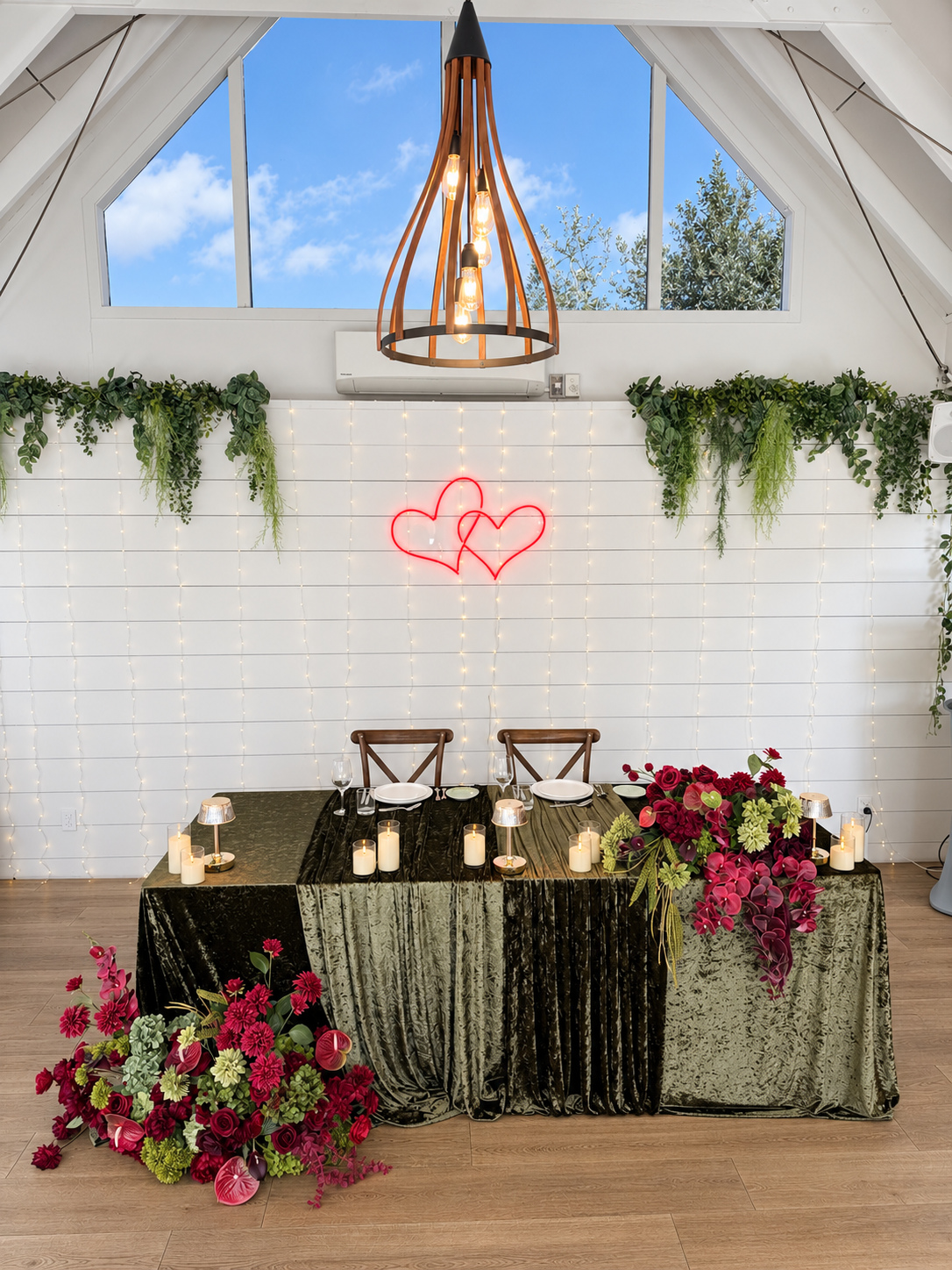 Crimson and chartreuse sweetheart table for two with olive-green velvet, cascading burgundy florals, lime-green accents and candles.